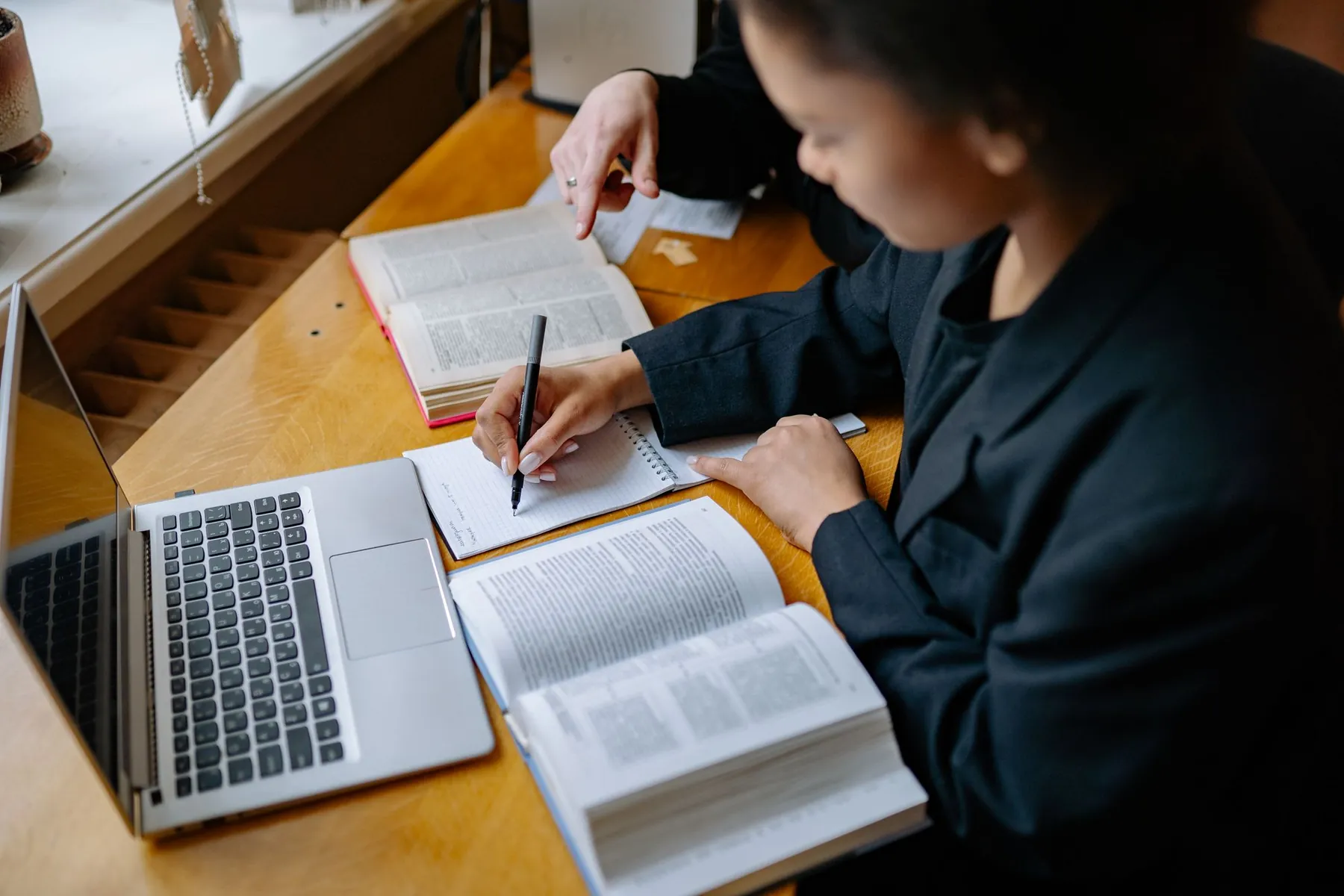 A student taking notes beside books and a laptop