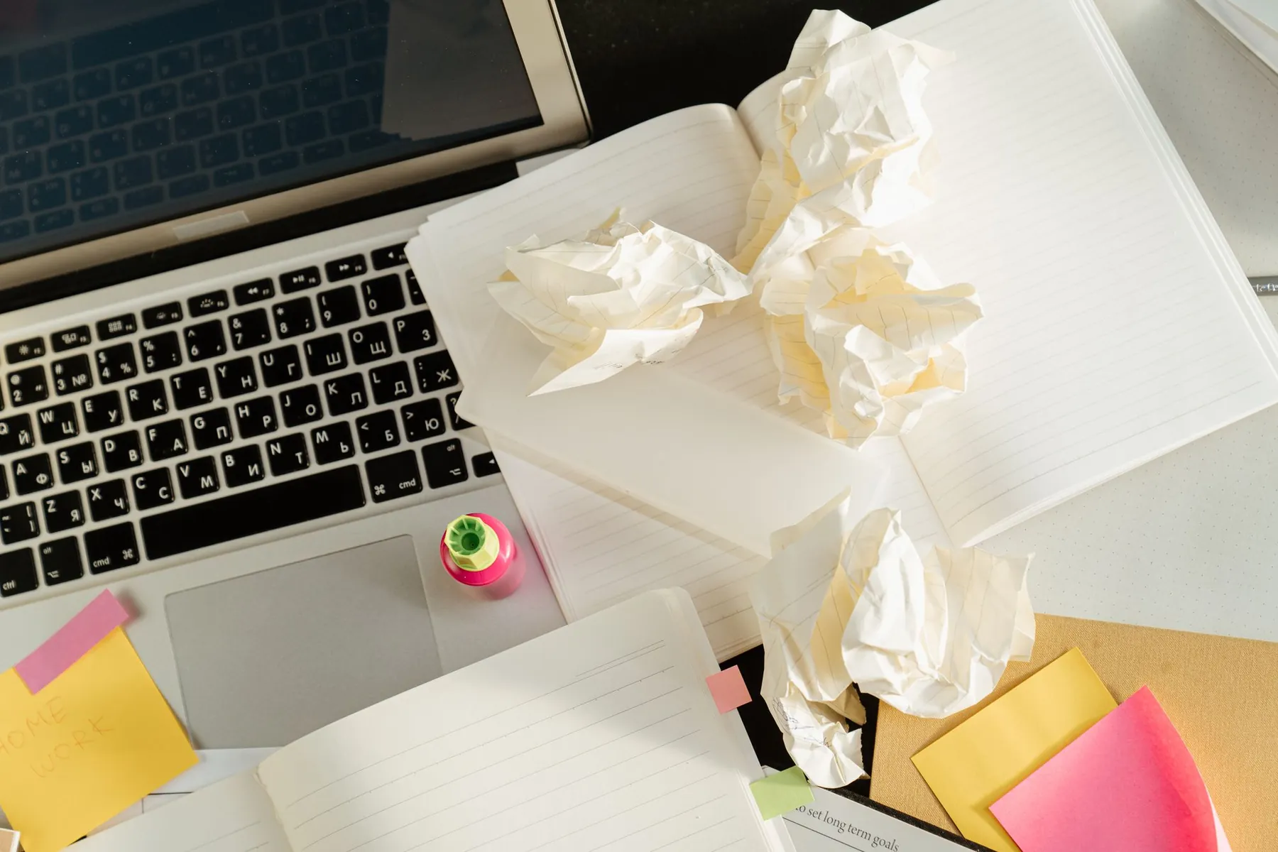 Crumpled sheets of paper on a laptop beside sticky notes