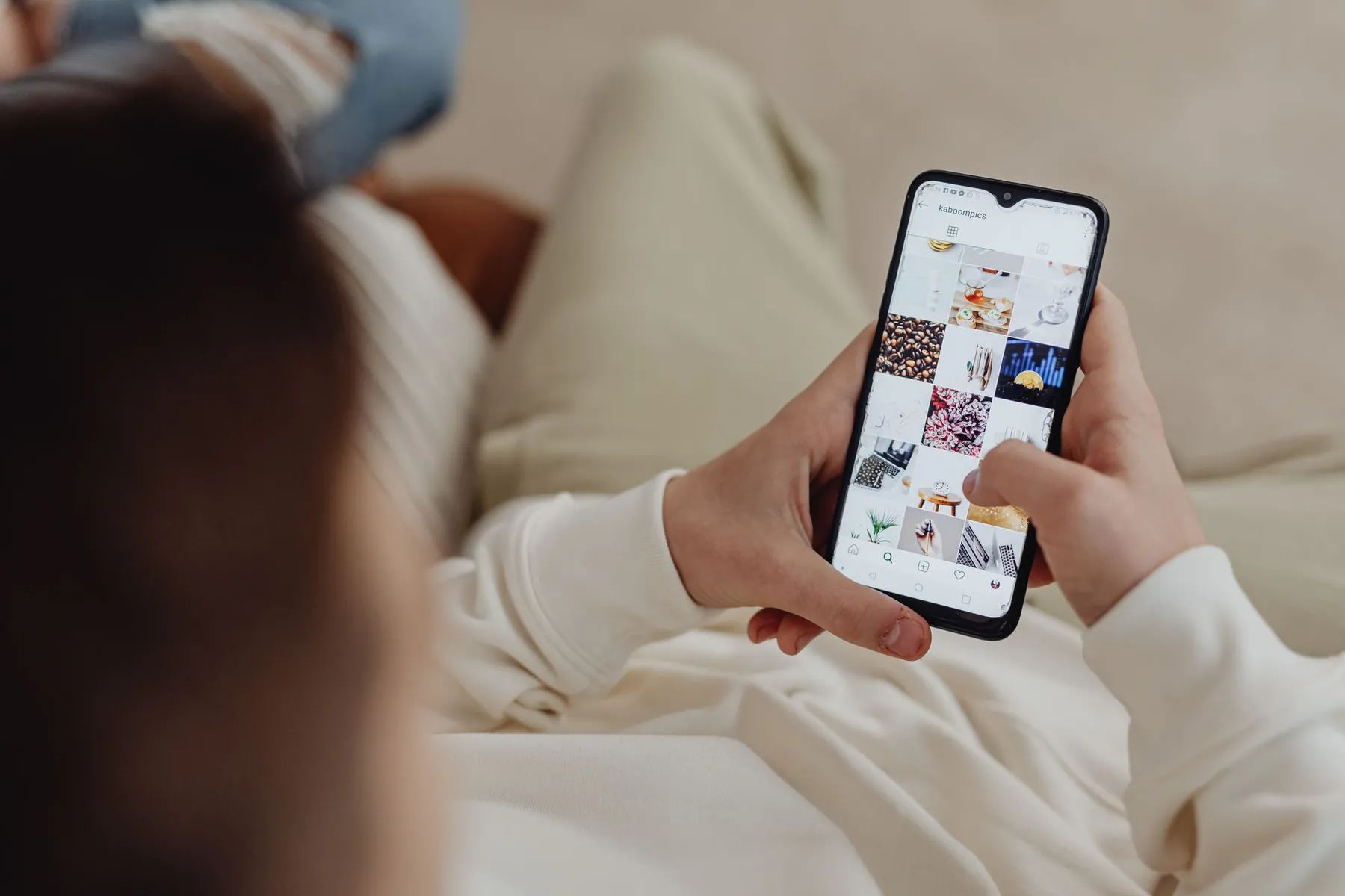 Hands scrolling a social media feed on a phone