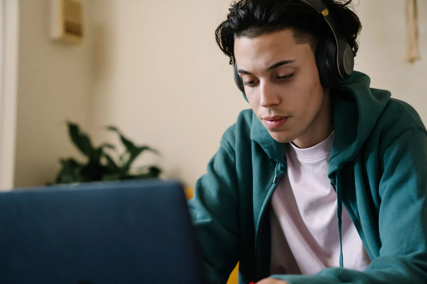 A young man in headphones working on a laptop