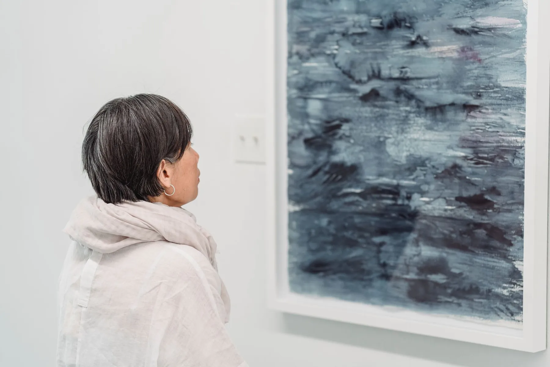 A woman looking at an abstract painting in a gallery