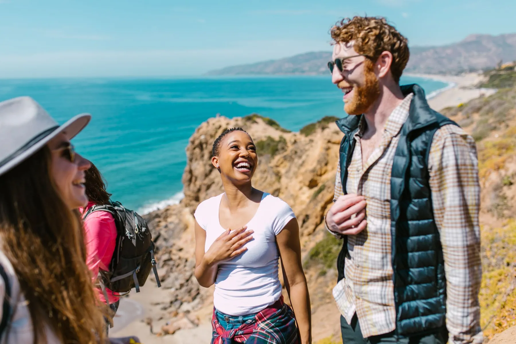 Friends laughing together on a walk above the sea