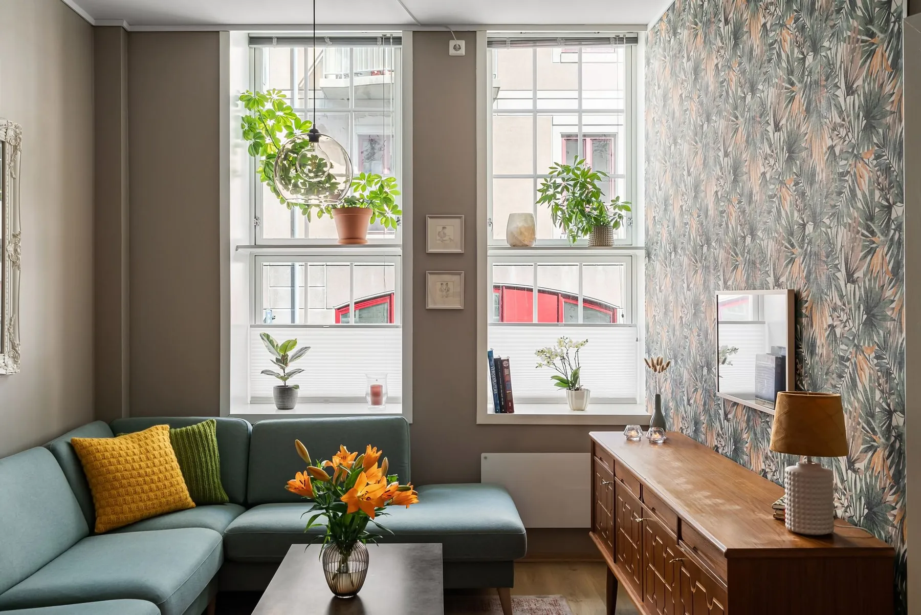 A cosy living room with plants and a green sofa