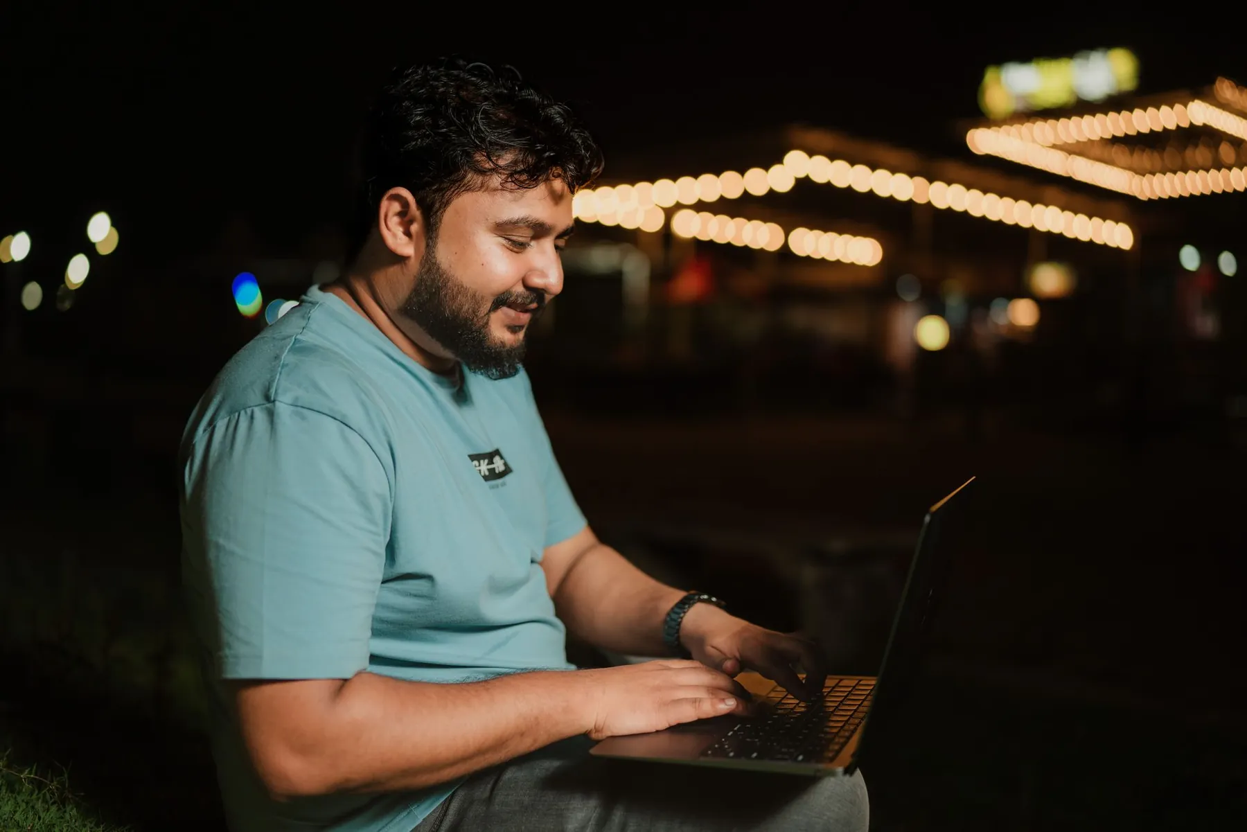 A man working on a laptop outdoors in the evening