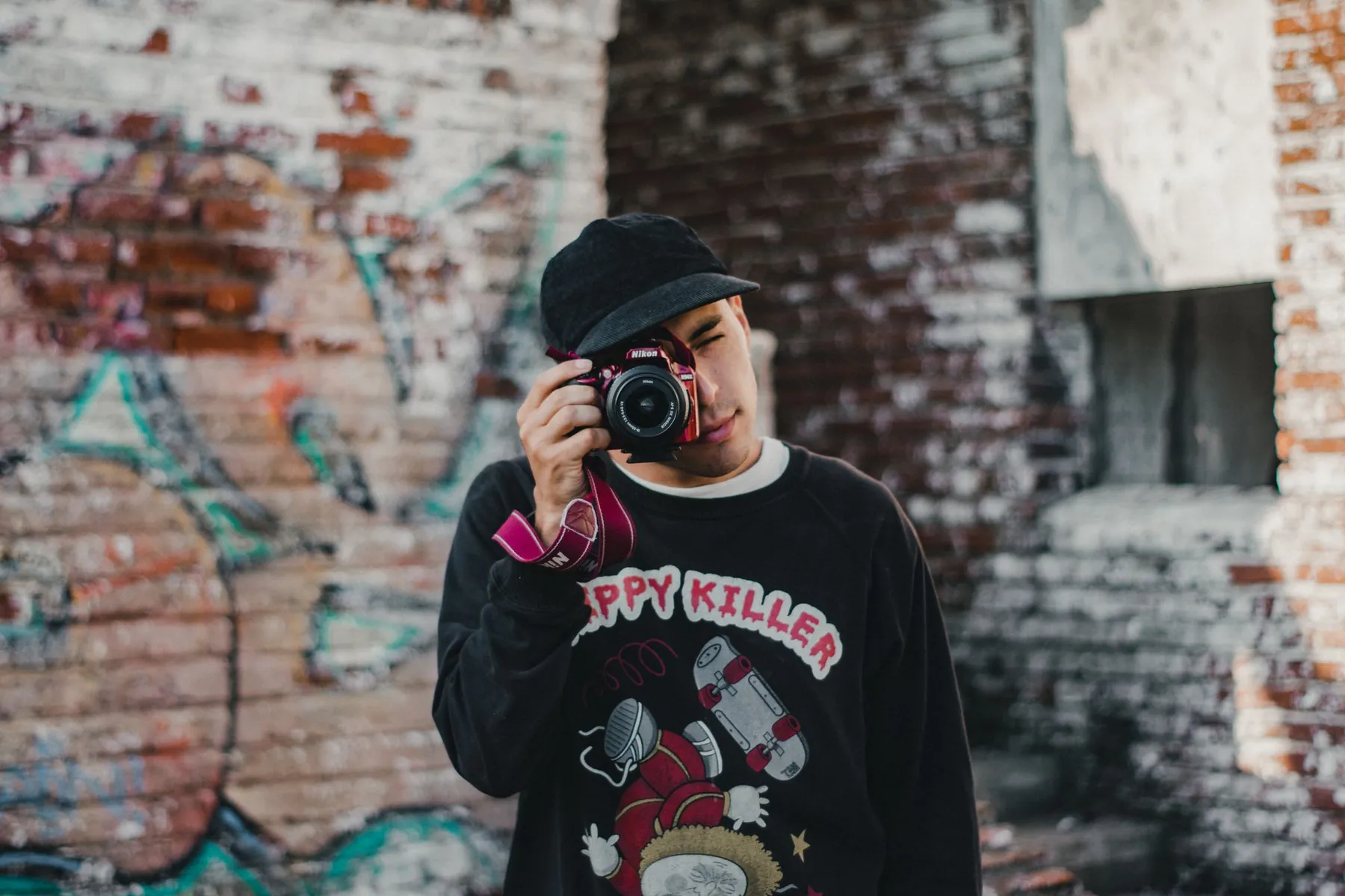 A young man taking photos in front of a graffiti wall