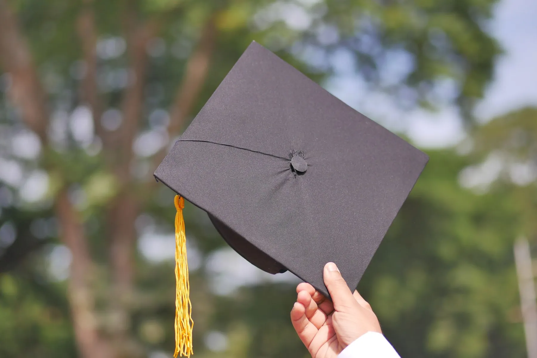 A graduation cap held up in one hand