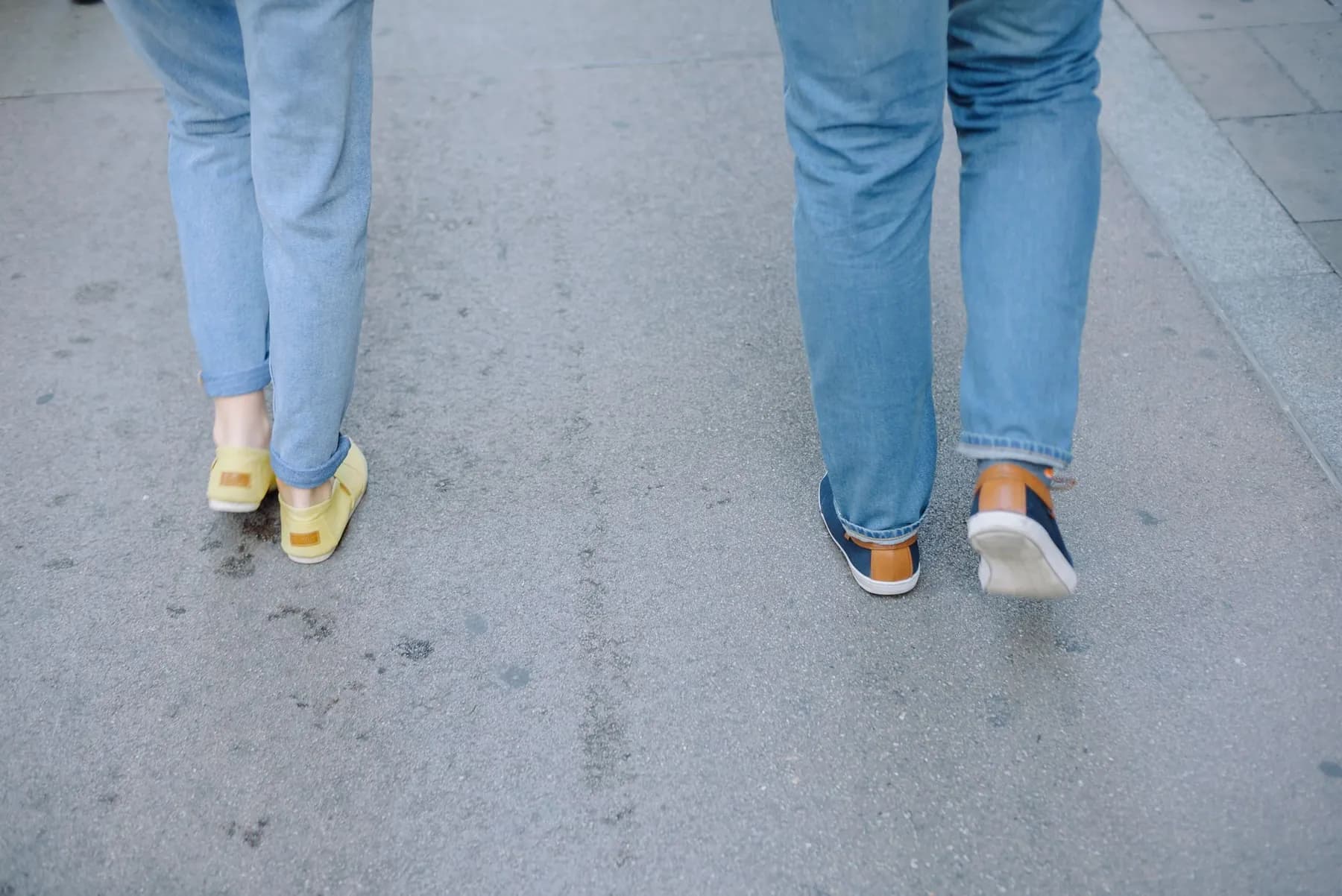 Two people walking along a city pavement