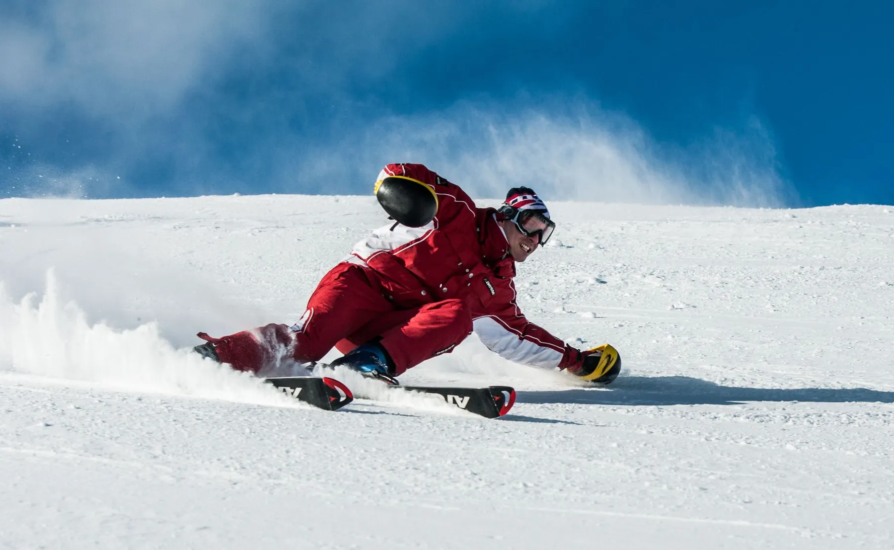 A skier in red carving down a snowy slope
