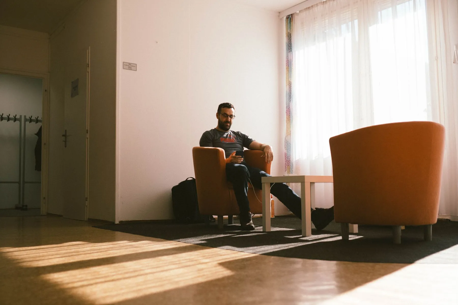 A man waiting in a sunlit lounge