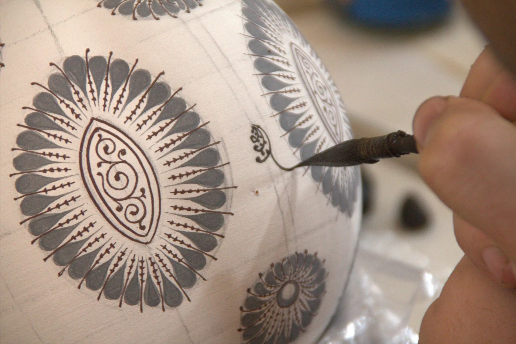 A craftsman hand-painting patterns on Uzbek ceramics