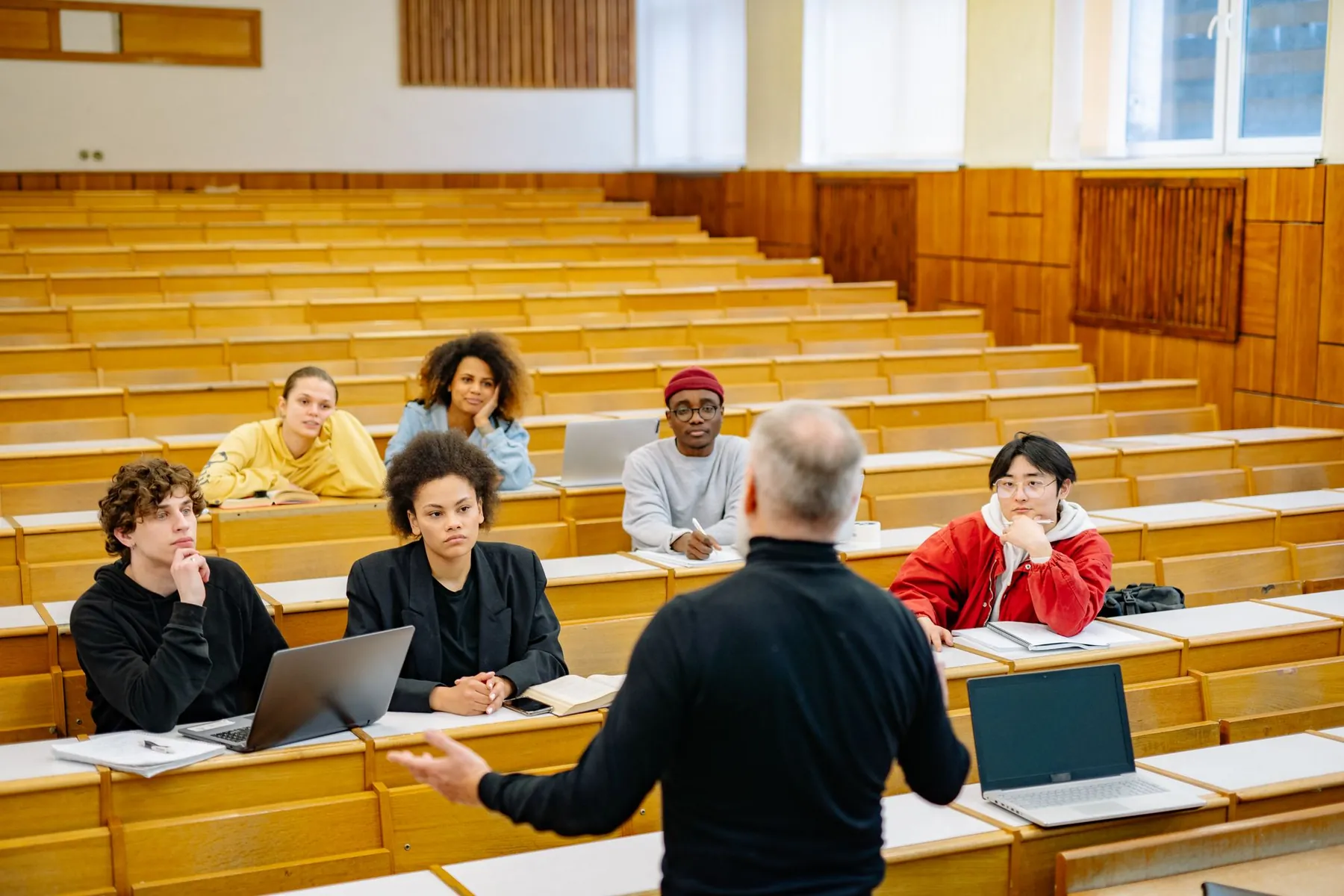 A lecturer talking with students in a lecture hall