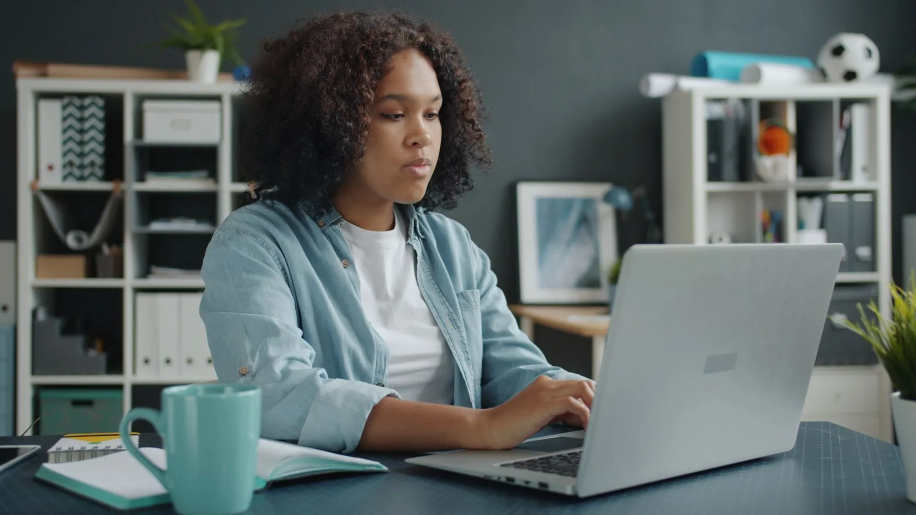 A woman working on a laptop at a desk at home