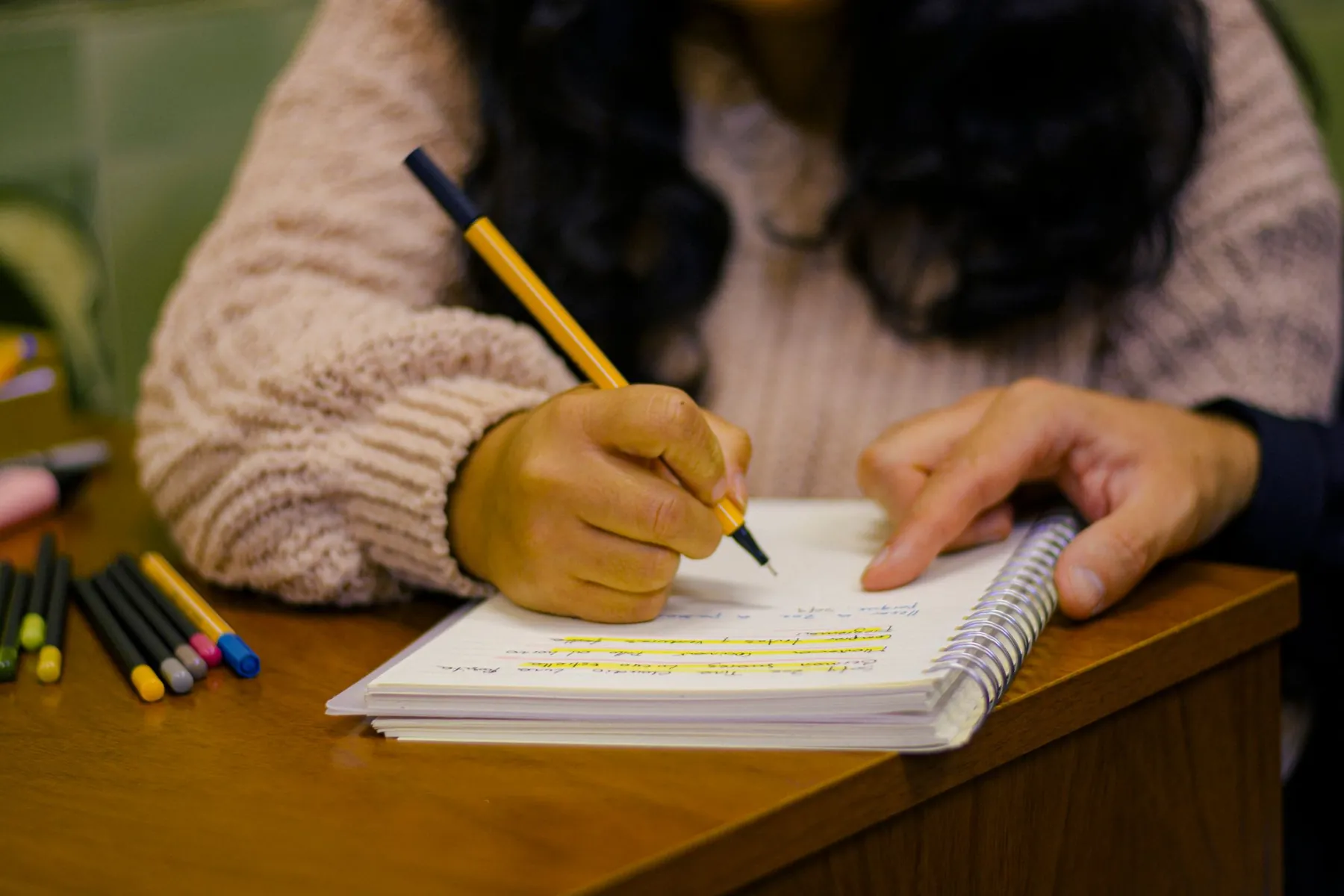 A student writing in a notebook, lines picked out in highlighter