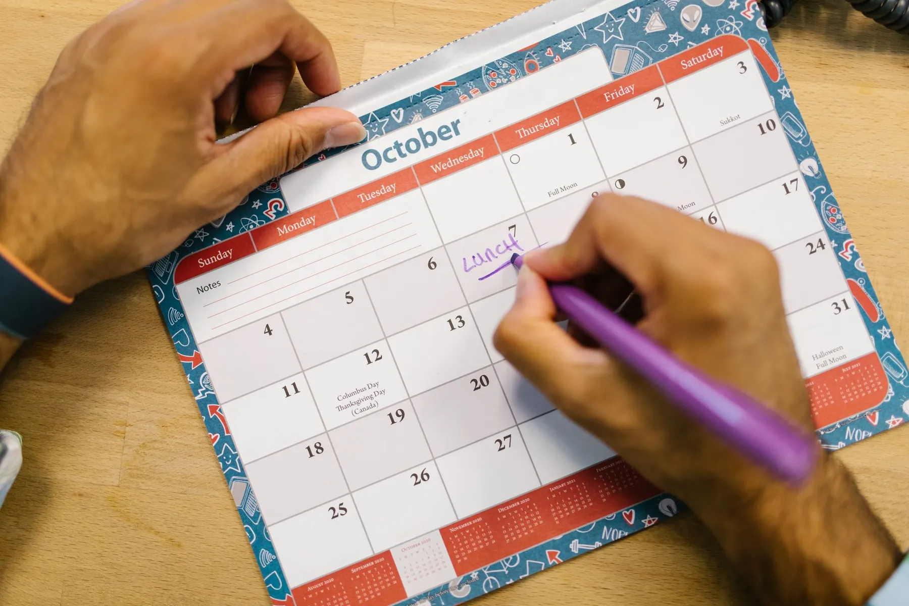 A hand writing a plan into a monthly calendar