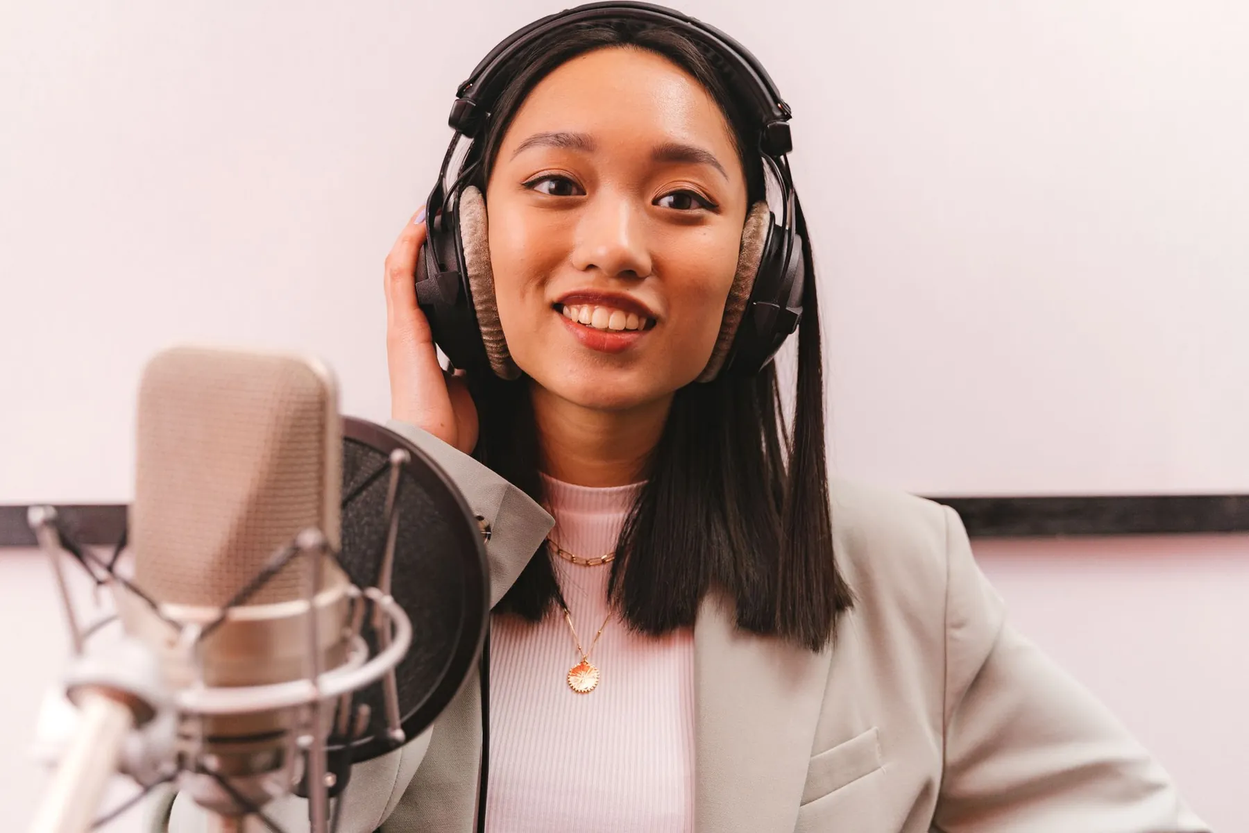 A woman in headphones speaking into a studio microphone