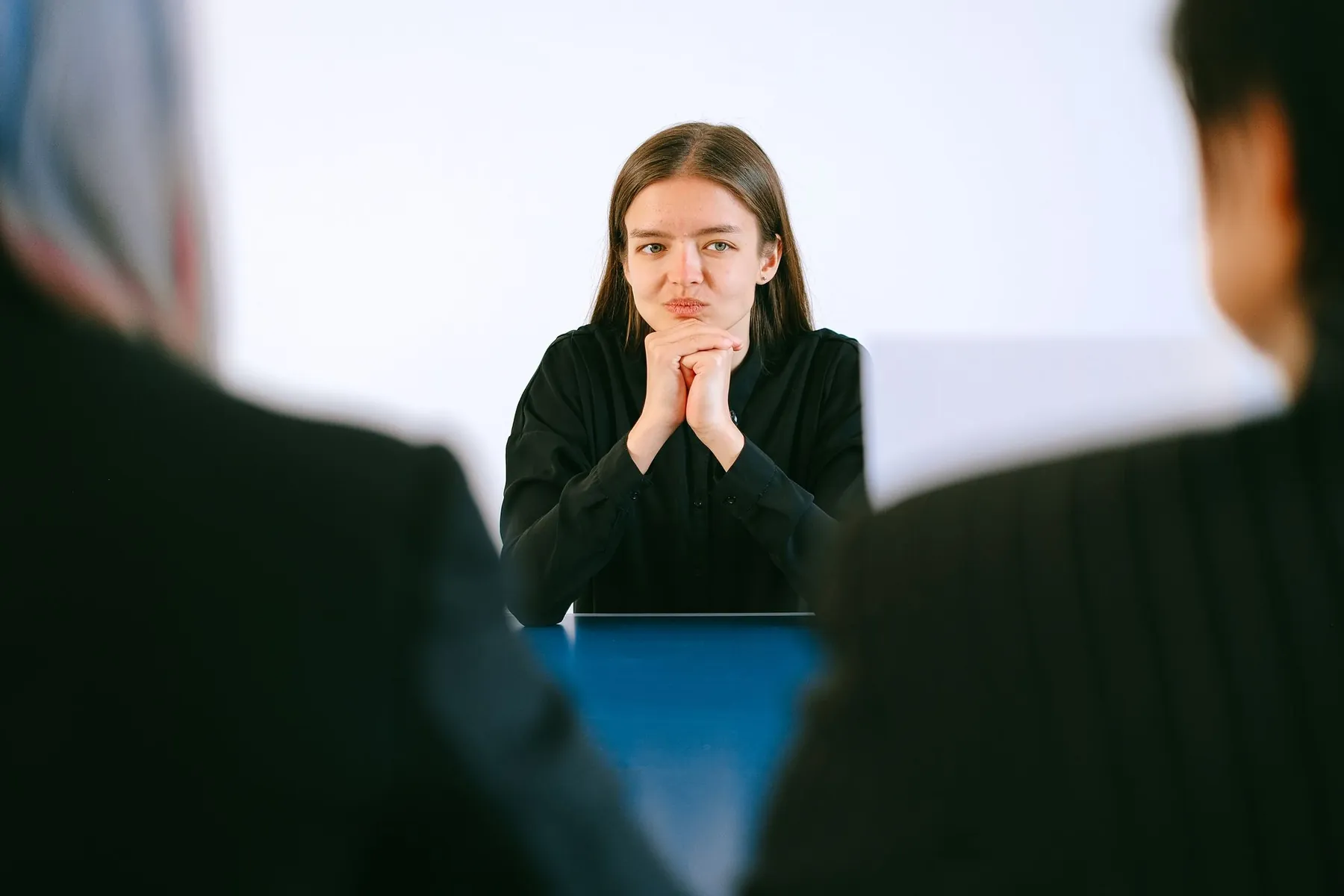 A candidate sits facing two examiners, ready to speak